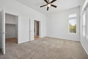 An empty living room with a ceiling fan and a closet